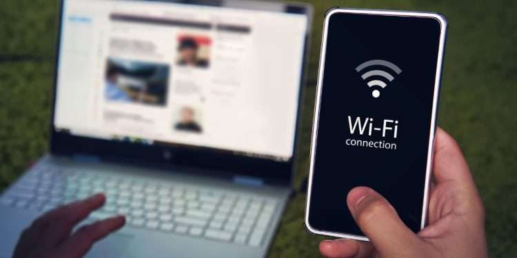 Vemos una imagen de una persona compartiendo wifi de su celular a su computadora, en referencia a la pregunta cómo ocultar mi red wifi.